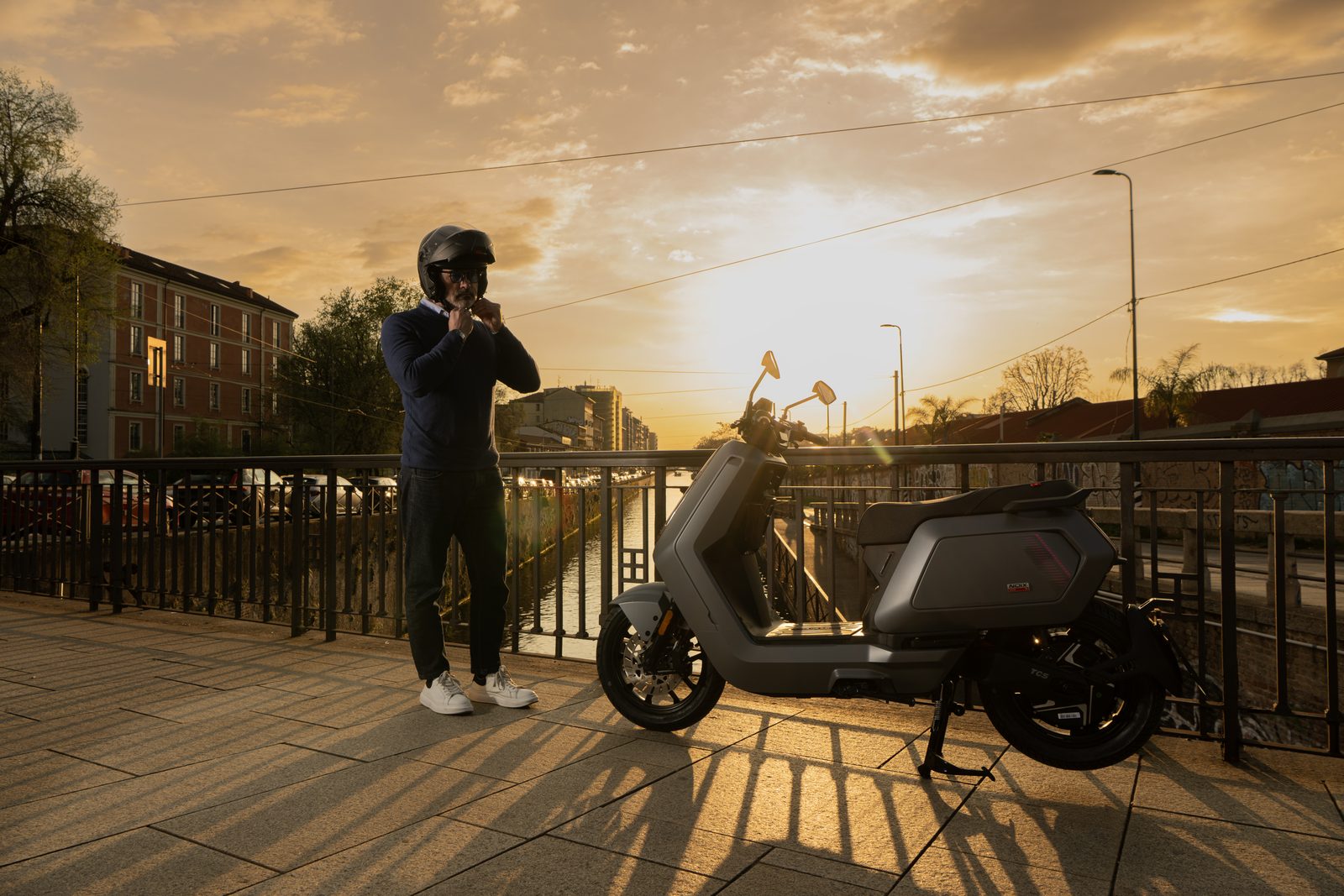Grauer NIU NQiX 500 MY26 an einer Brücke bei Sonnenuntergang